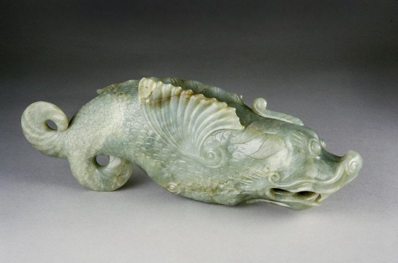 Greenish white carving of a fish-dragon creature.