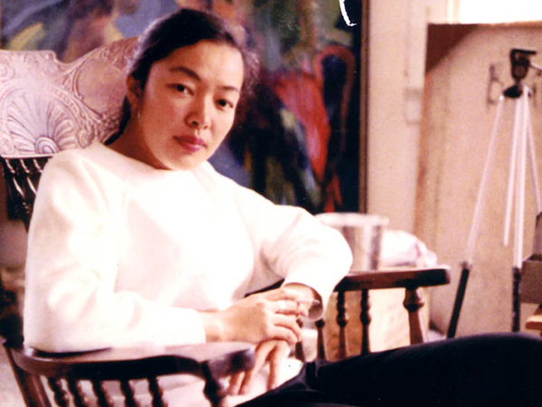 Portrait of a woman in a white sweater sitting in a chair.