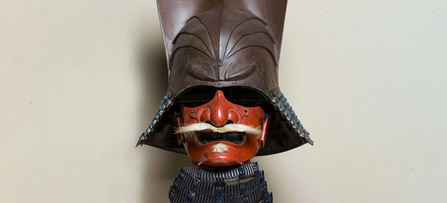Detail of red mask with a metal helmet and hairy moustache.